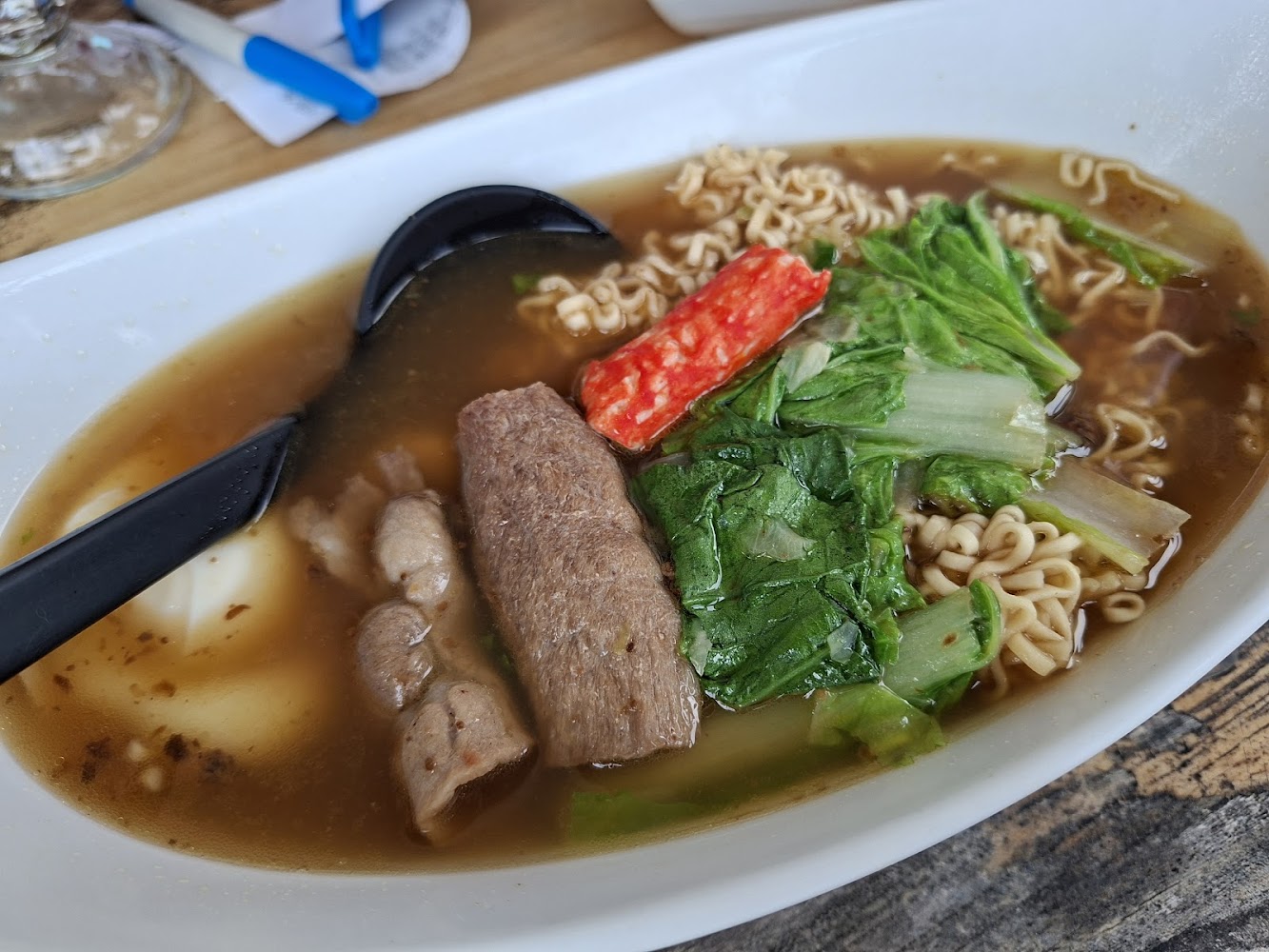一碗湯麵，裡面有速食麵、牛肉片、魚板、蔬菜和一顆水煮蛋