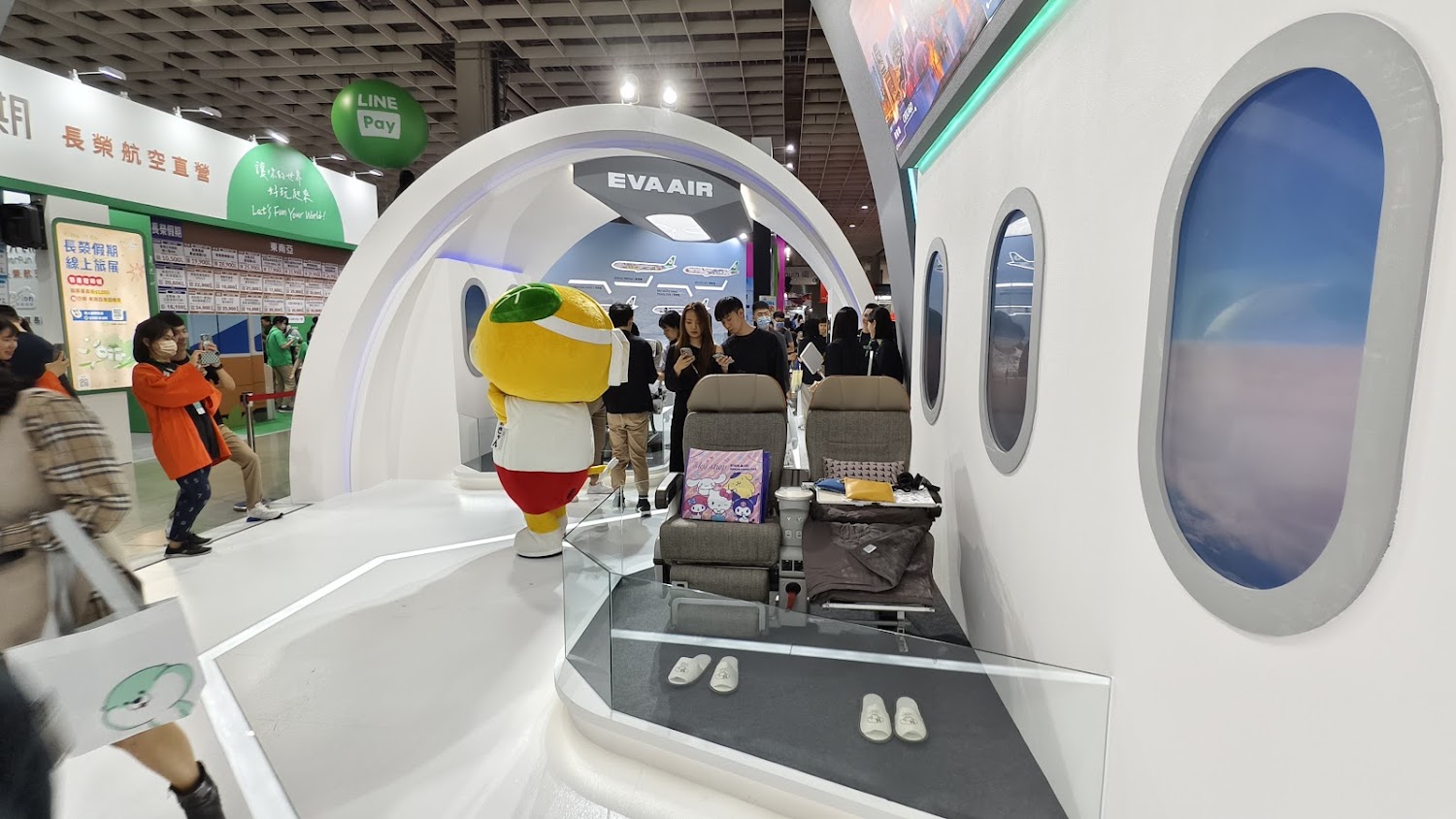 長榮航空展示攤位有飛機座椅與卡通吉祥物,模擬機艙氛圍吸引民眾體驗