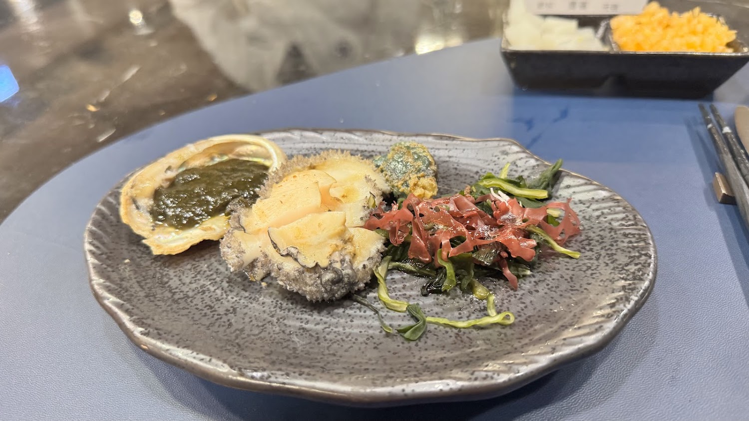 精緻海鮮料理以鮑魚切片搭配海藻與鮑魚殼盛裝
