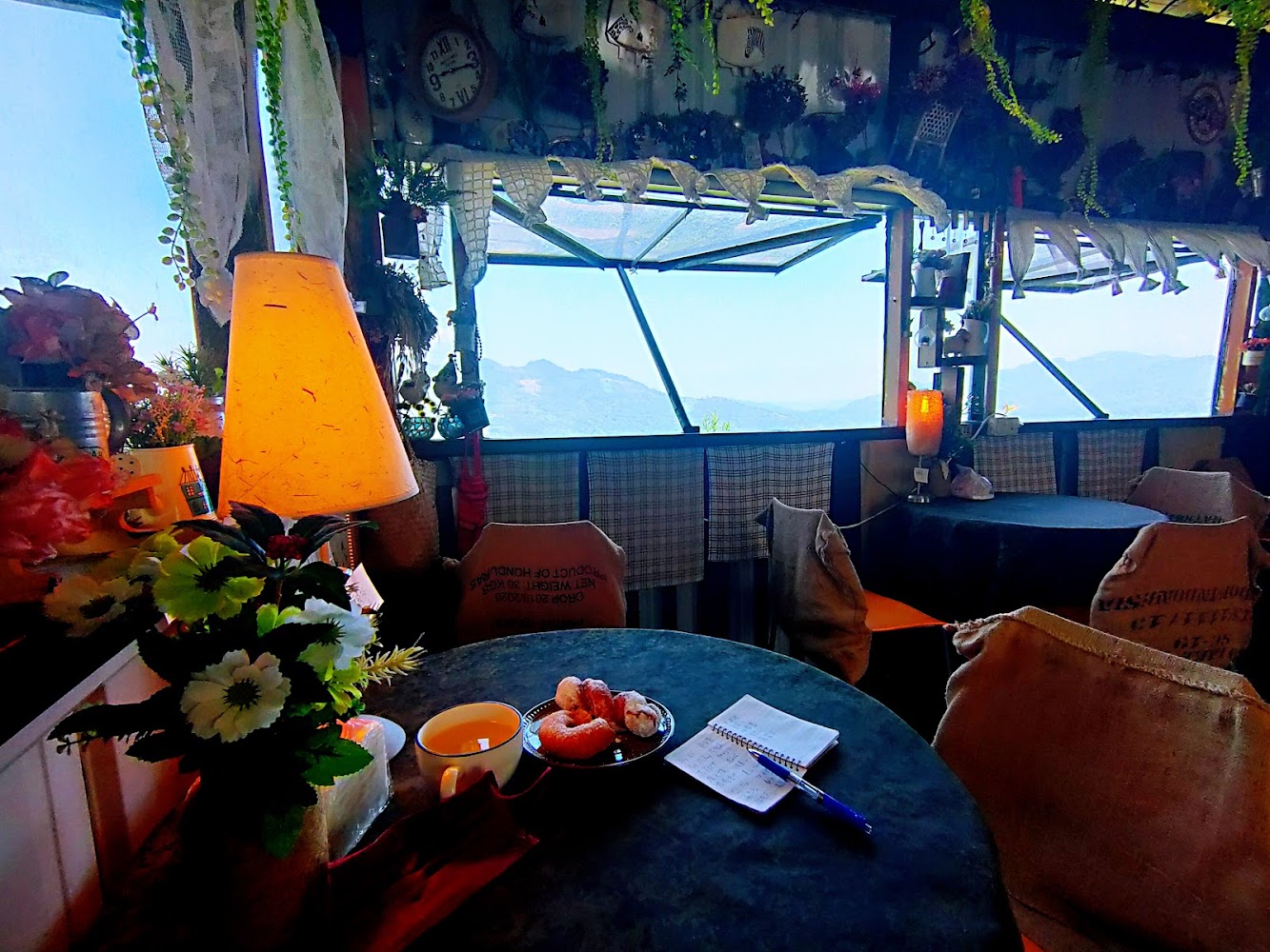 咖啡館室內桌上擺著花卉飲品點心與山景窗景