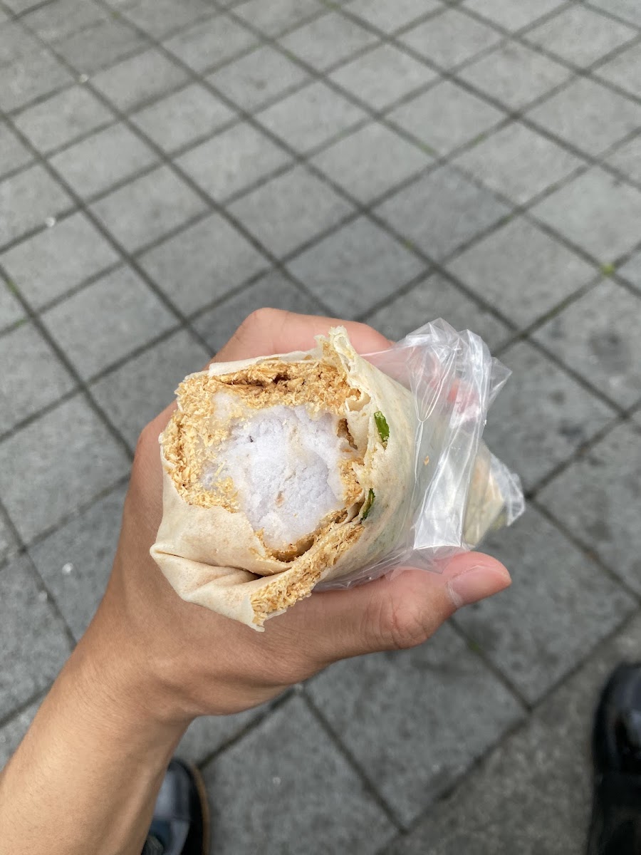 手持吳記花生捲冰淇淋，潤餅皮包覆冰淇淋與花生糖粉