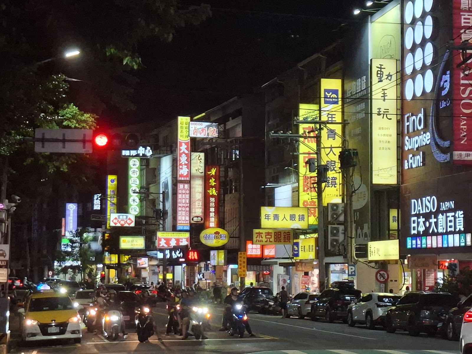 逢甲夜市周邊文華路夜景，霓虹招牌林立，機車車陣等候紅燈
