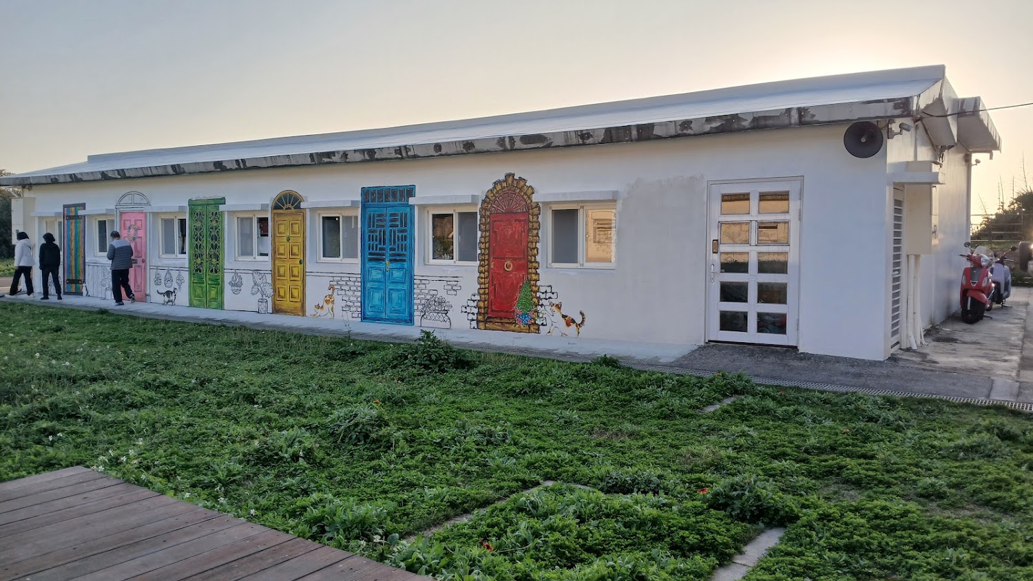 白色建築彩色門壁畫與草地