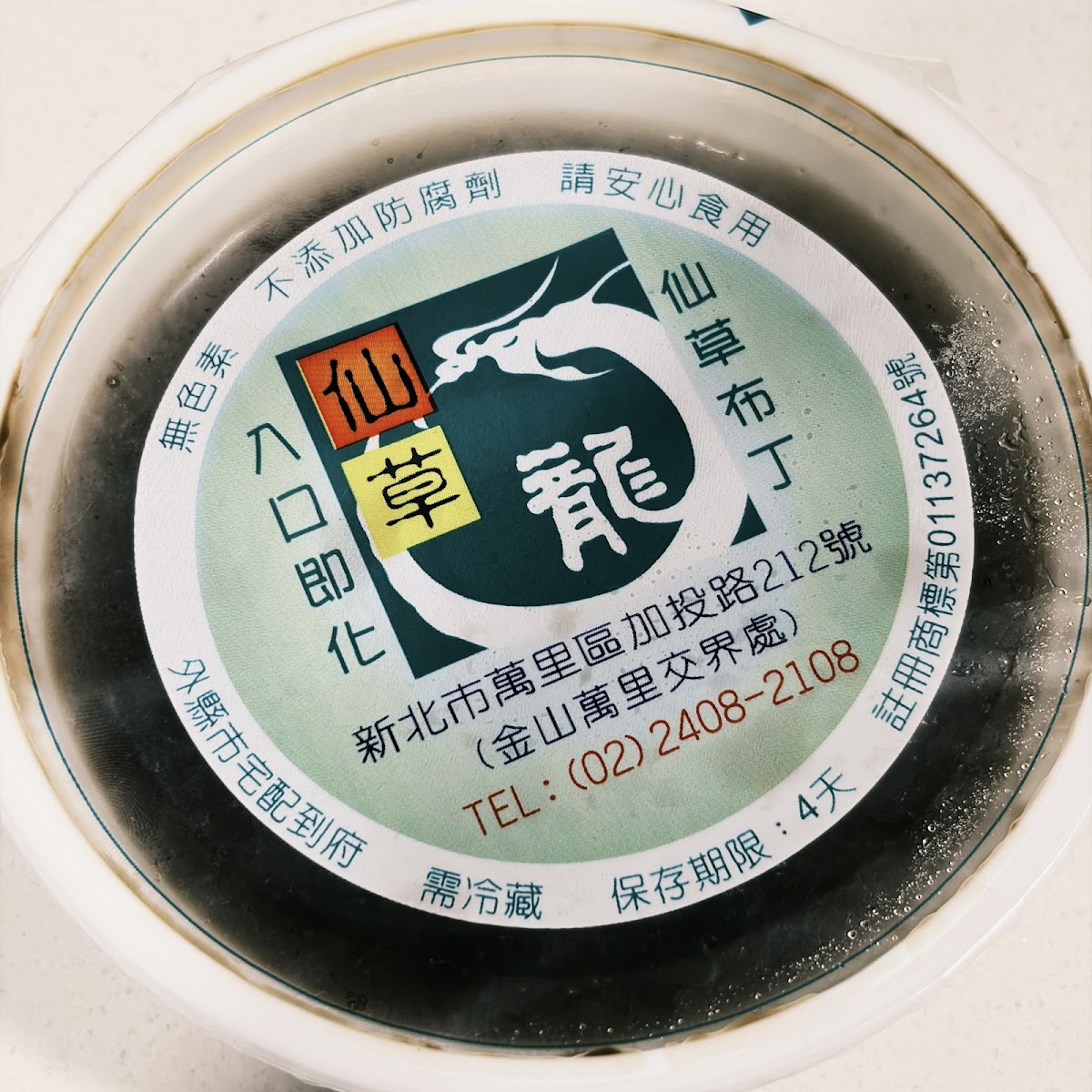 仙草龍仙草布丁盒蓋，印有品牌logo與地址，入口即化字樣引人食慾
