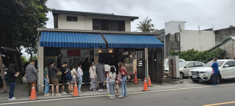 纏記舊街東河包子店門口大排長龍，藍色遮陽棚下遊客等候