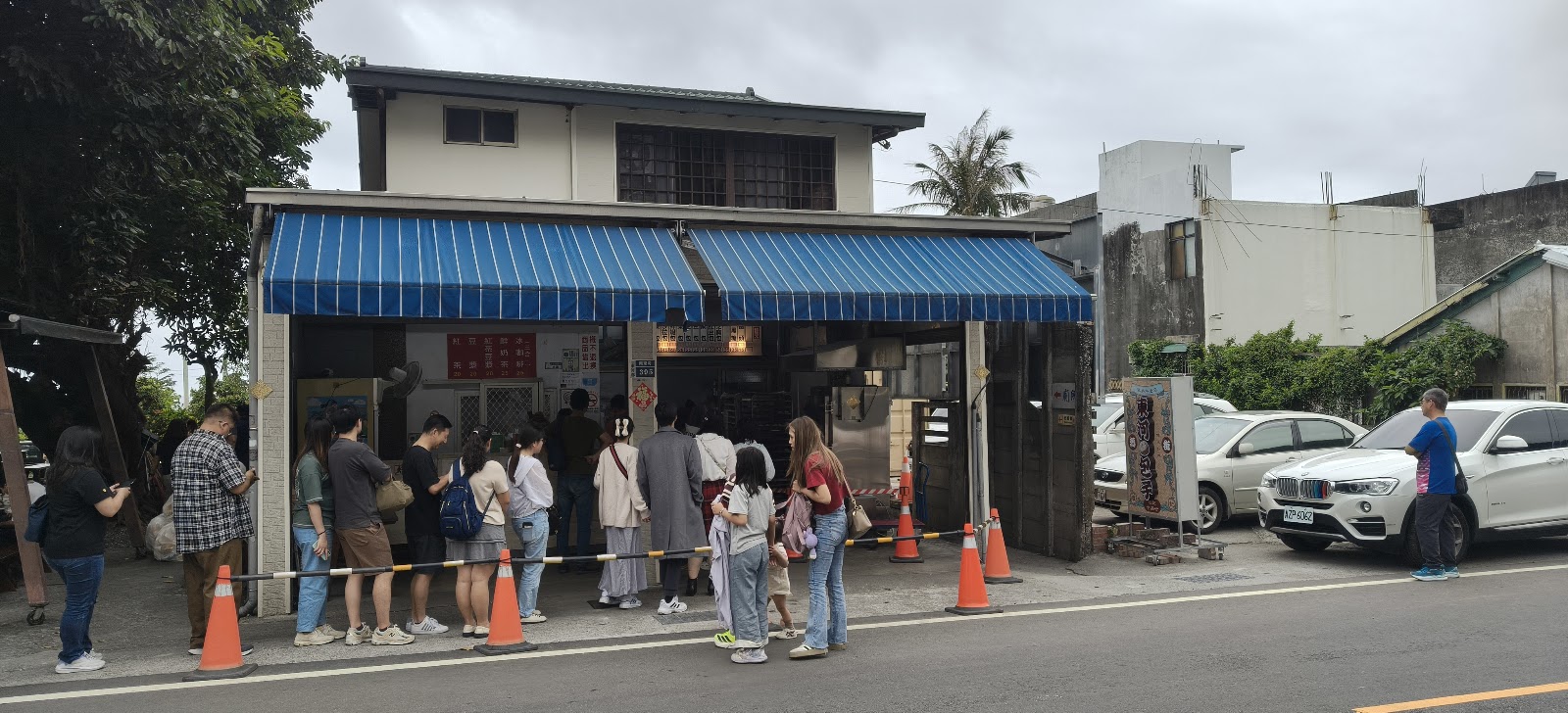 纏記舊街東河包子店門口大排長龍，藍色遮陽棚下遊客等候