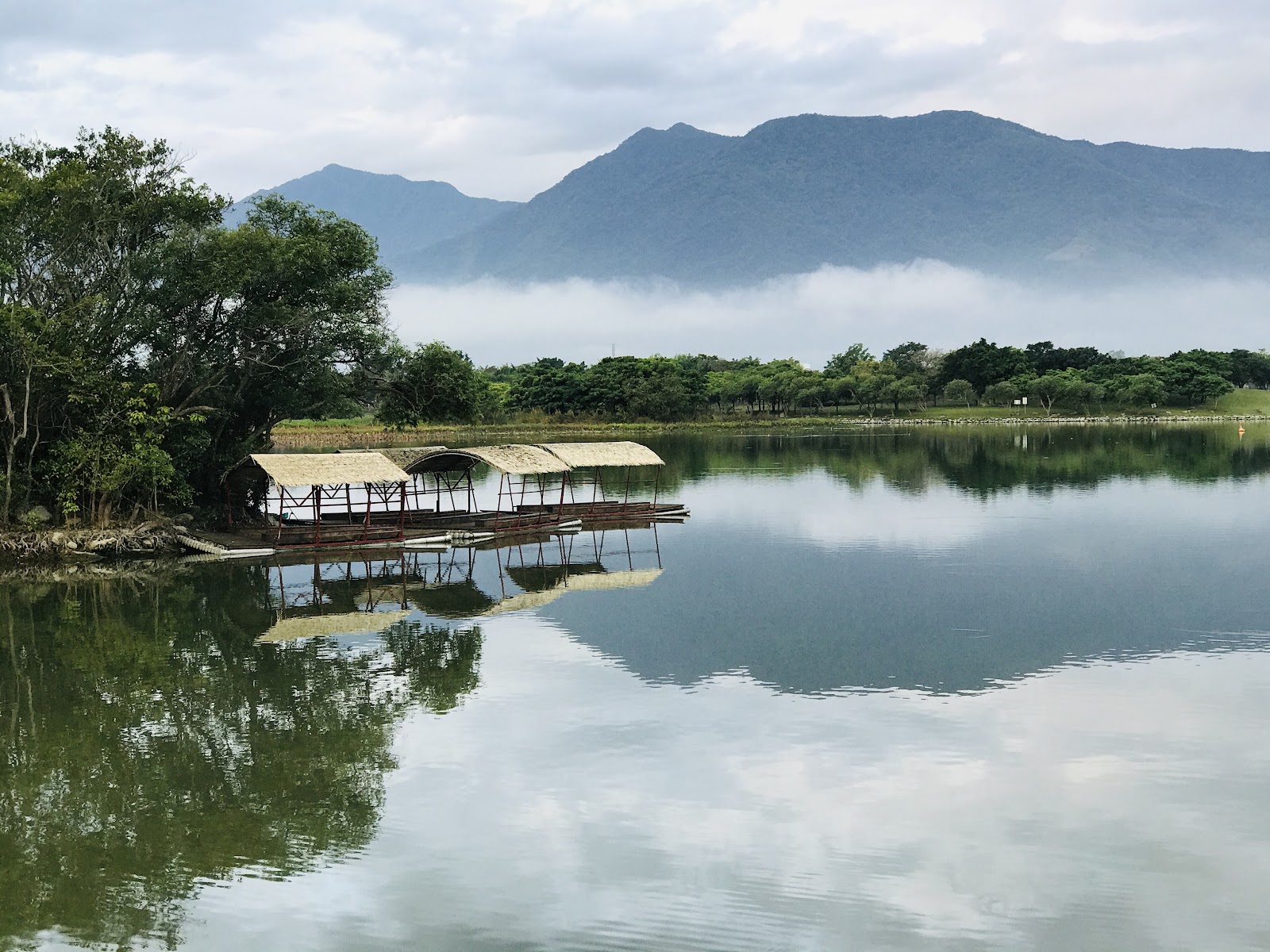 大坡池竹筏棧台倒映湖中，晨霧繚繞，山景如夢似幻