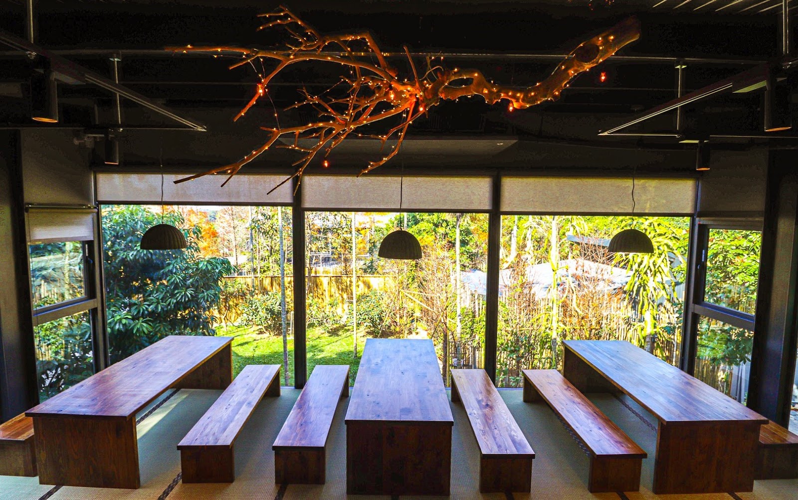 紙箱王餐廳室內空間，天花板樹枝造型燈飾裝置藝術，木質長桌，大片落地窗