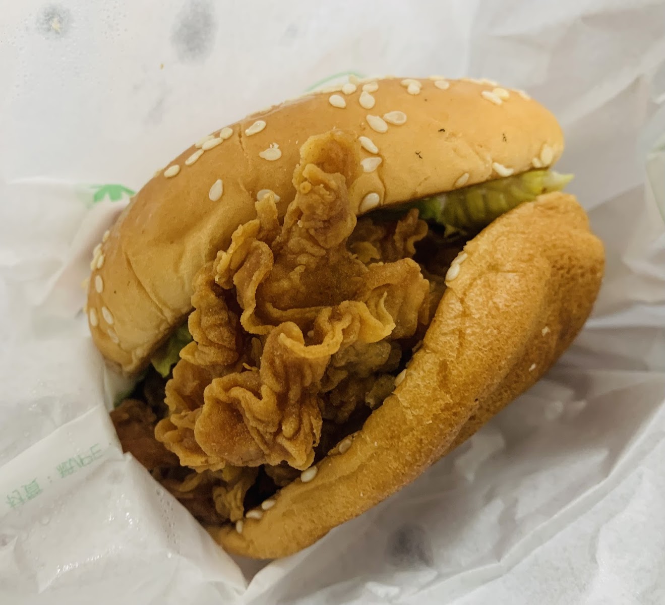 丹丹漢堡梓官店鮮脆雞腿漢堡特寫，酥脆炸雞腿溢出漢堡外