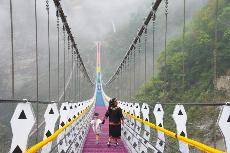南投信義鄉雙龍七彩吊橋，橋面七彩繽紛，遊客漫步其上，背景雲霧繚繞峽谷
