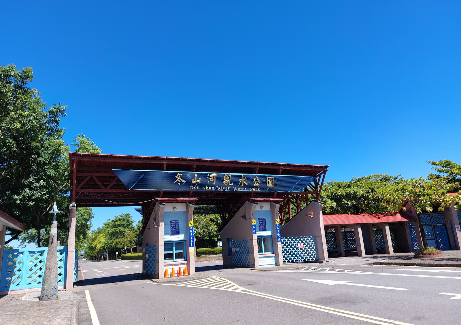 冬山河親水公園正門入口，藍底金字招牌，紅棕色棚架，湛藍晴空