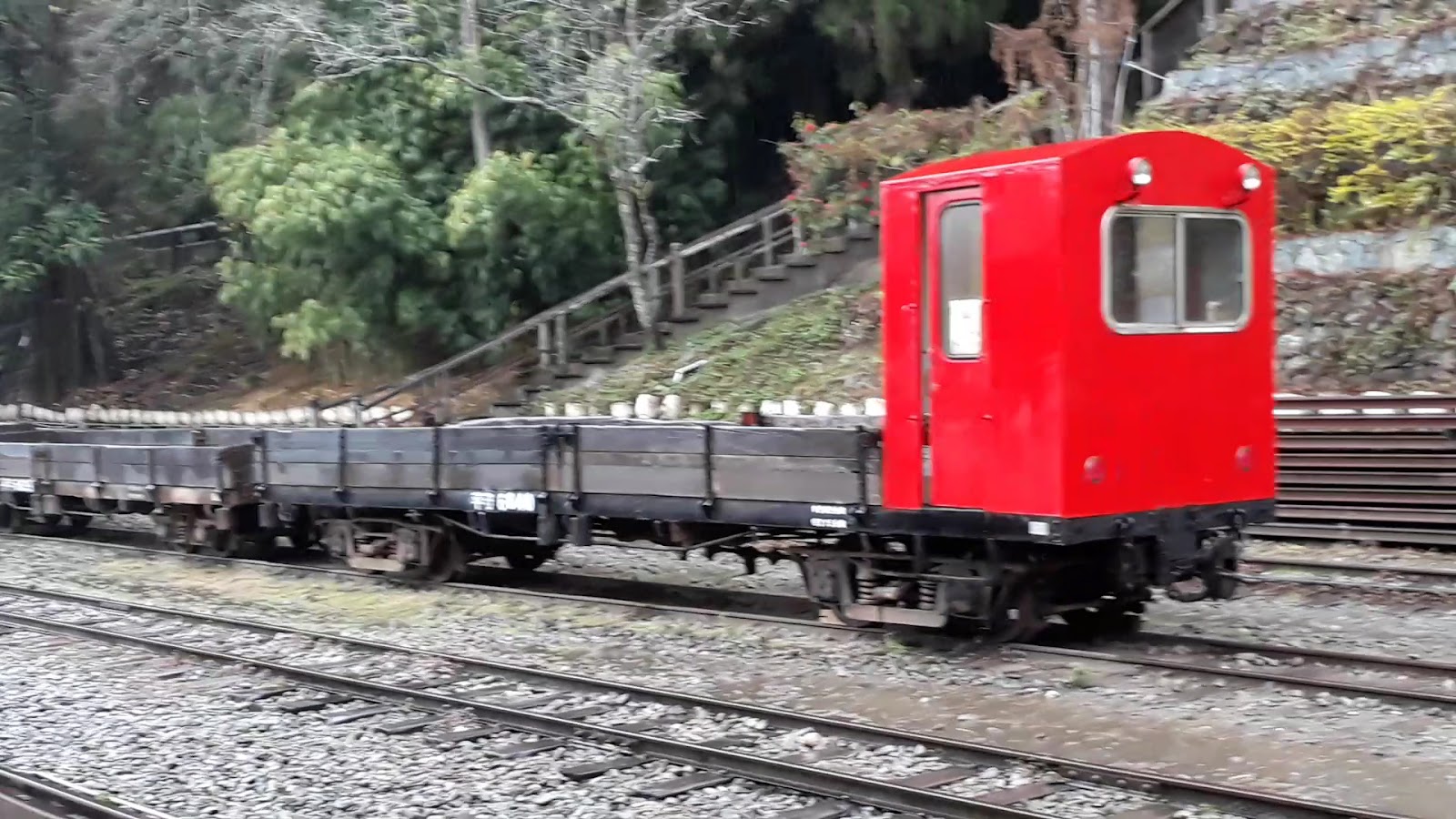 鮮紅調車機車頭與舊式貨車在碎石軌道上