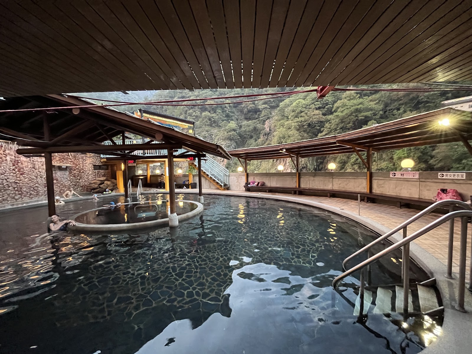 谷關溫泉飯店傍晚露天溫泉池，暖色燈光，泡客靜享青山景色
