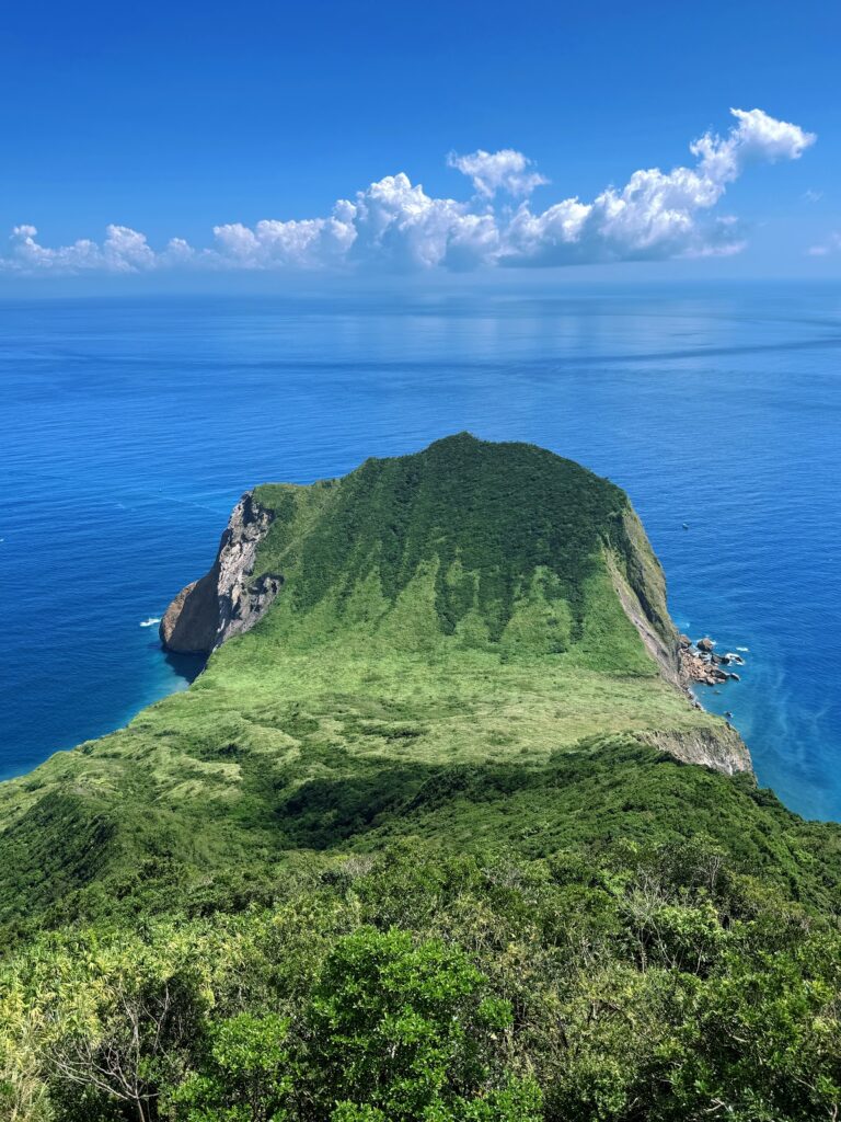 宜蘭龜山島空拍俯瞰，翠綠植被覆蓋的島嶼被湛藍海水環繞