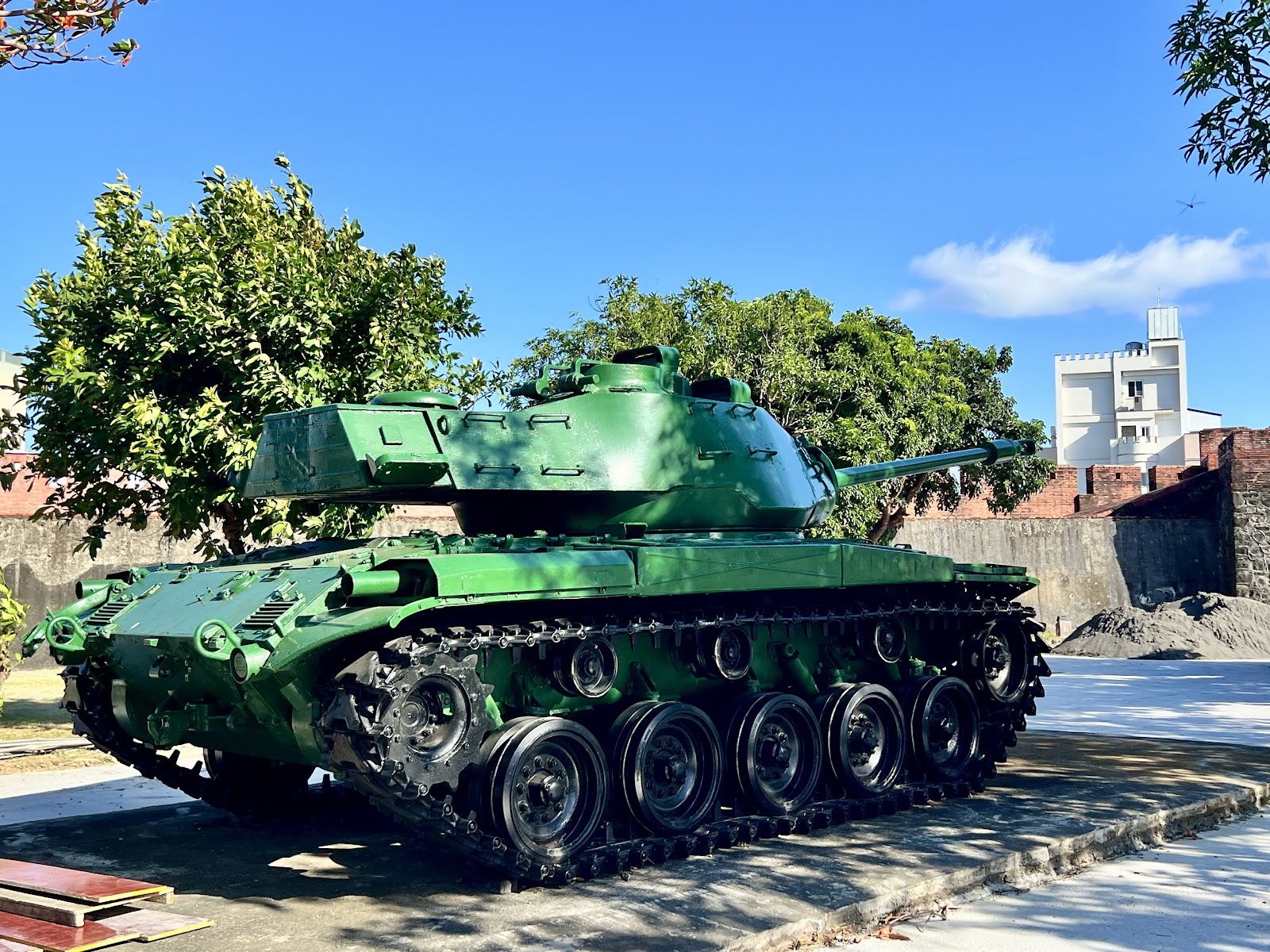 恆春古城牆旁綠色軍用坦克展示，背景為紅磚城牆與晴空藍天