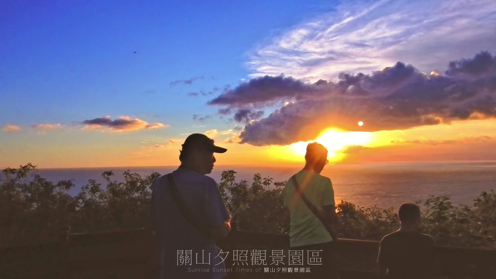 關山夕照觀景園區兩位遊客剪影背對橙金色夕陽，海天輝映壯麗