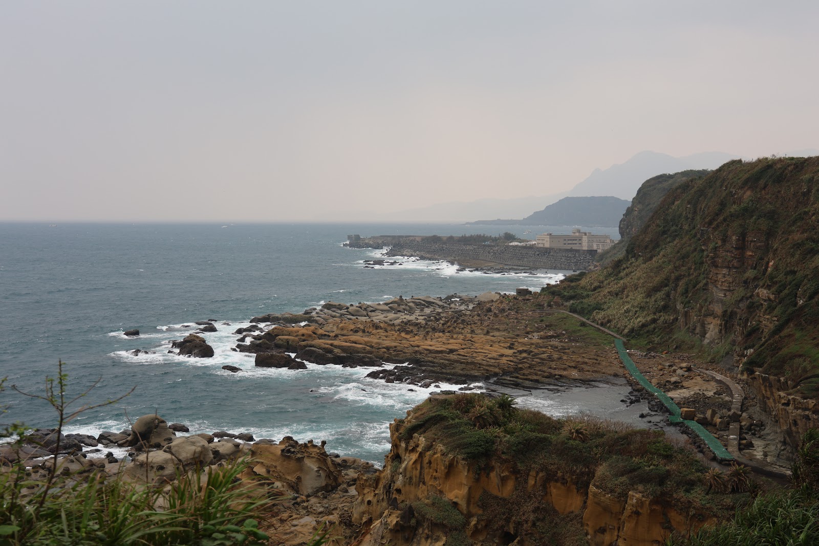 從環山步道高處俯瞰和平島海岸,白浪拍岸礁石,右側陡峭海蝕崖