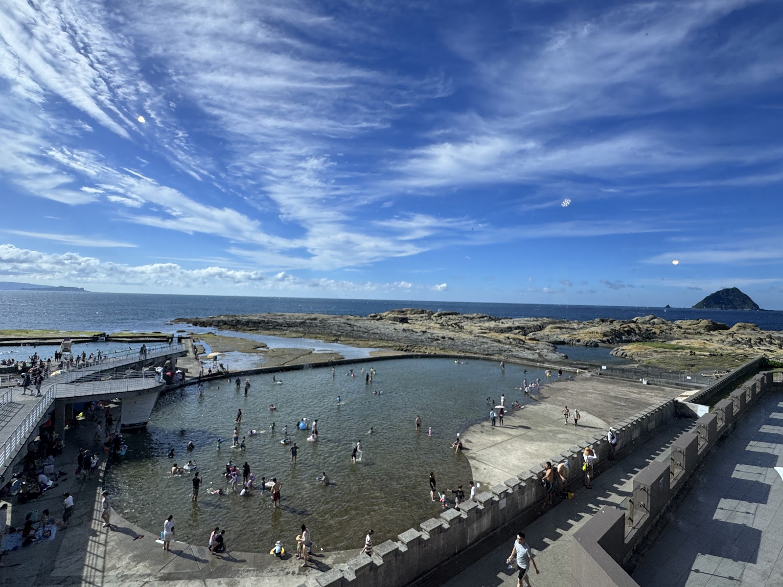 和平島海水游泳池俯瞰,假日遊客眾多,背景是基隆嶼與藍天白雲