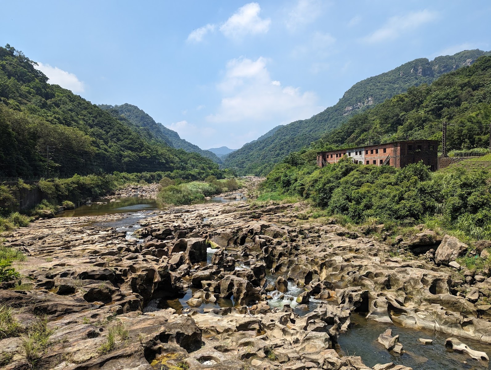 基隆河溪床壺穴地形，大石遍布，溪水在石縫間流淌，遠處翠山環抱