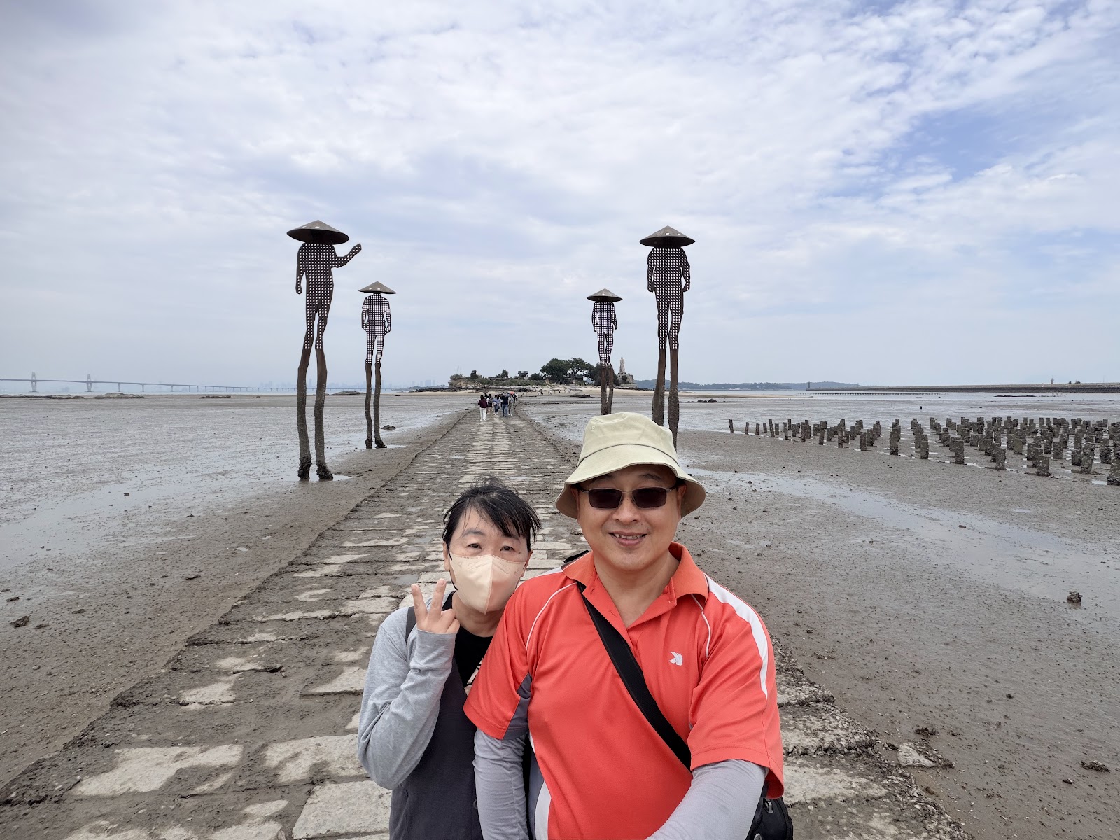 建功嶼石板步道，遊客漫步其上，兩側雕塑立柱，金門一日遊必訪景點