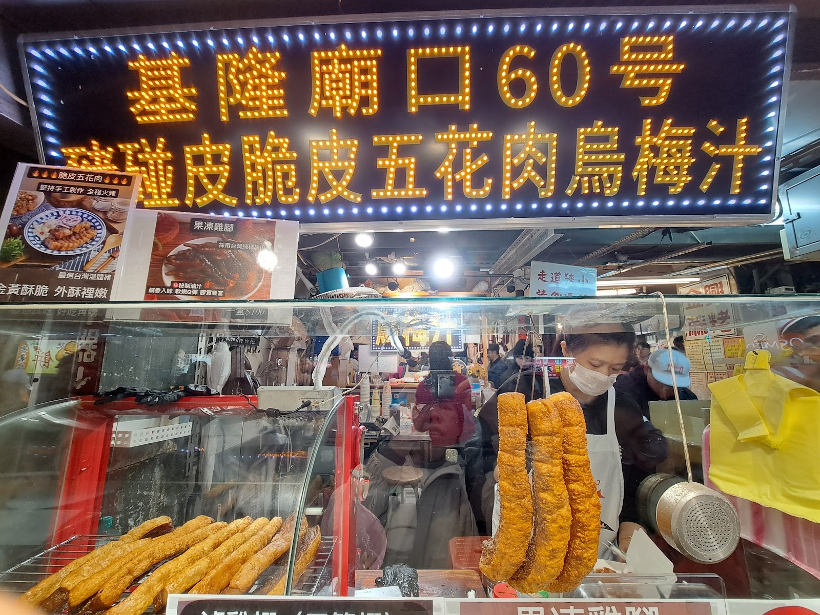 基隆廟口60號脆皮五花肉烏梅汁霓虹燈招牌，攤前排列金黃脆皮肉串