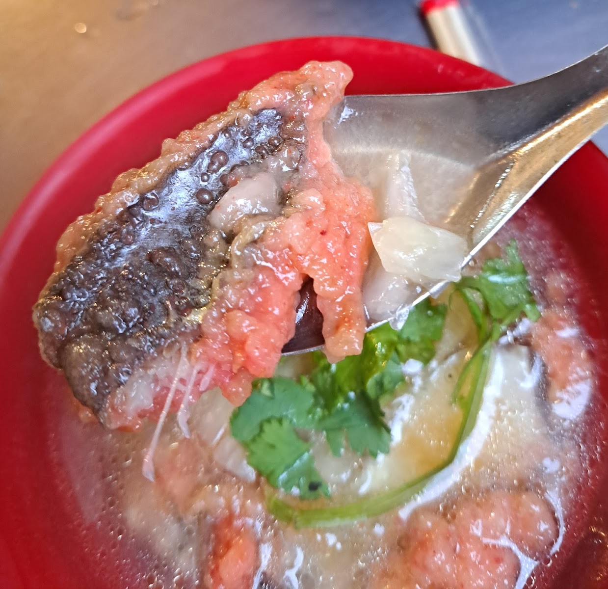 基隆廟口夜市鼎邊趖近照，紅碗盛白色薄片，清甜湯底旁有香菜