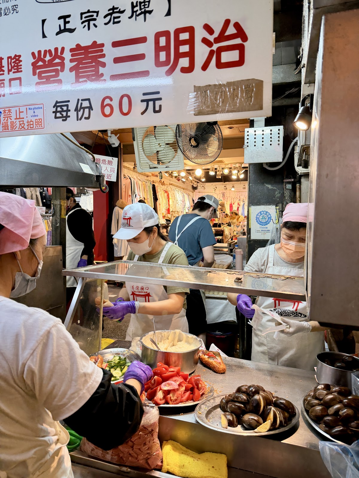 廟口夜市攤位內部，工作人員戴口罩手套認真備料