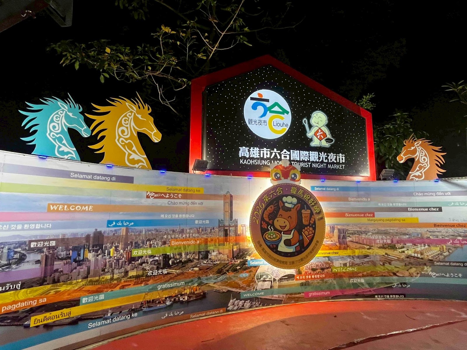 高雄市六合國際觀光夜市入口牌樓夜景，多國語言歡迎標語