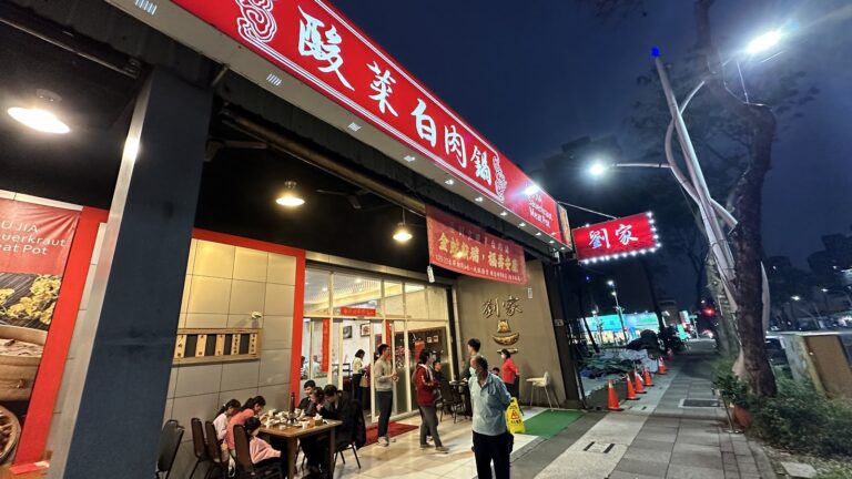 劉家酸白菜火鍋創始店夜晚外觀，紅色大招牌高掛、燈火通明，高雄左營眷村火鍋名店