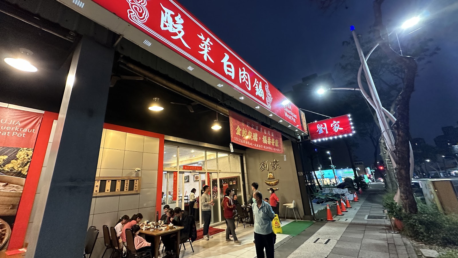 劉家酸白菜火鍋創始店夜晚外觀，紅色大招牌高掛、燈火通明，高雄左營眷村火鍋名店