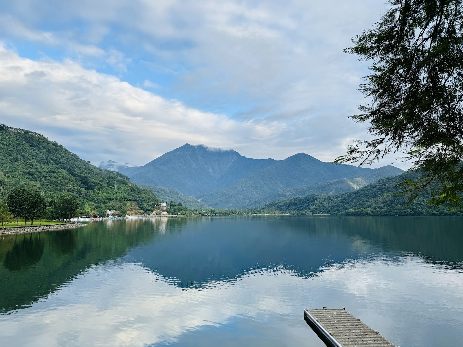 花蓮鯉魚潭湖面如鏡，清澈湖水倒映出層疊翠綠山脈，木製碼頭靜靜伸入水中