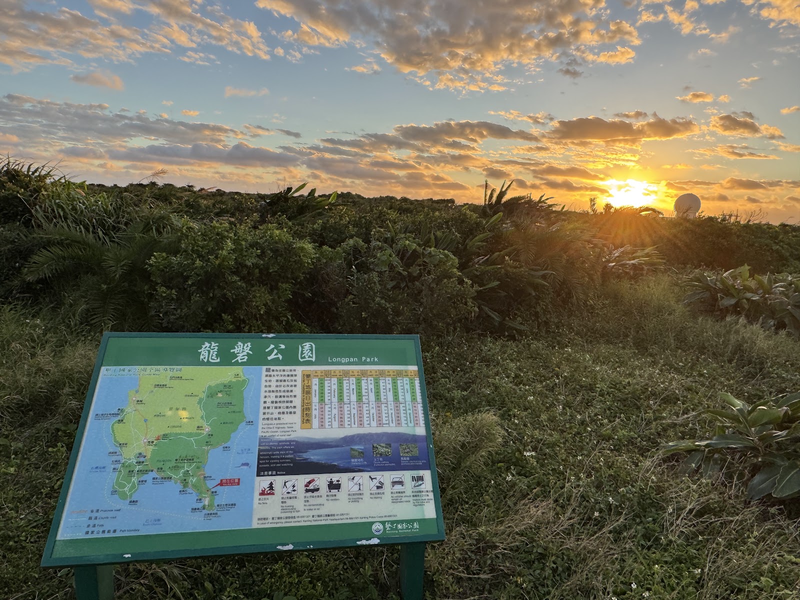 龍磐公園夕陽美景，公園說明牌前金光橙紅天空，墾丁必去景點