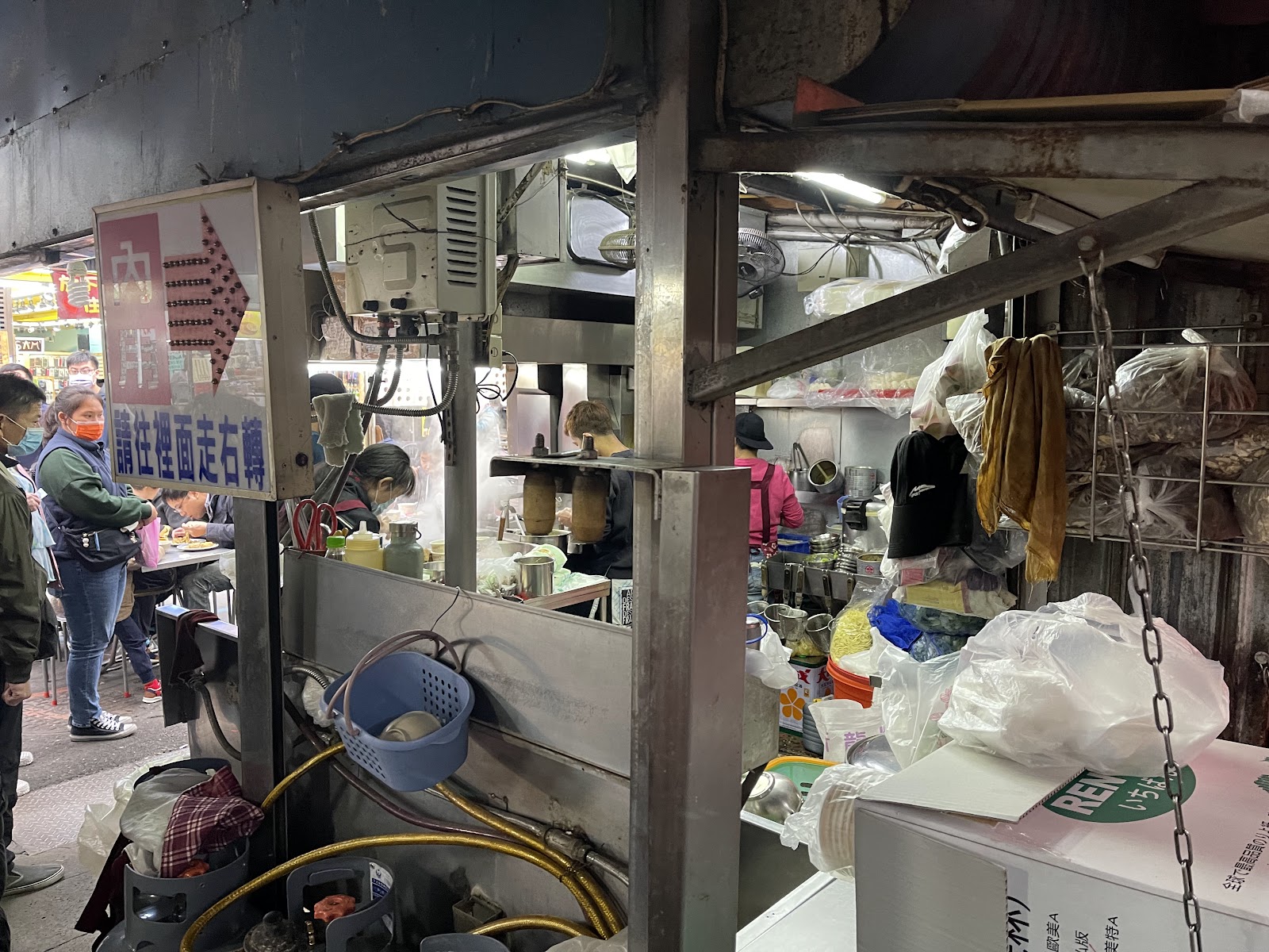 阿灶伯當歸羊肉湯夜市攤位，廚師忙碌烹調，顧客在戶外等候，請往裡面走右轉招牌