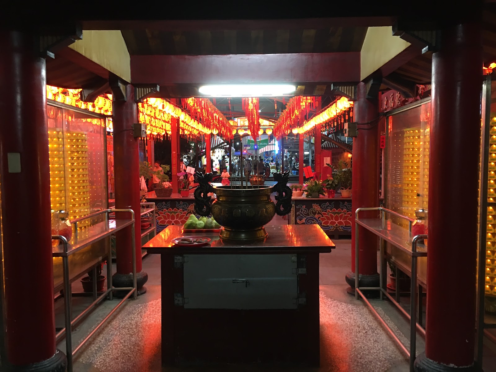 羅東夜市旁廟宇夜景，紅色柱子金色燈籠與香爐，背景可見夜市燈光