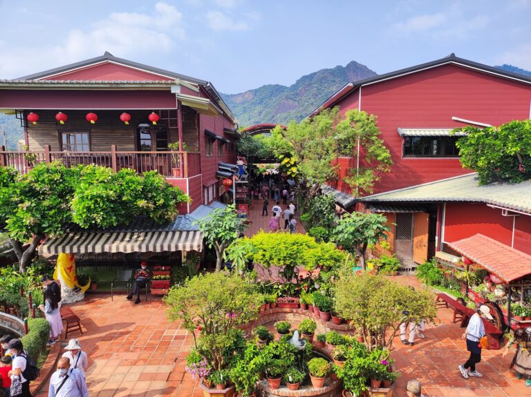 美濃民俗村俯瞰，紅色木造建築院落，旗尾山為背景，高雄美濃一日遊