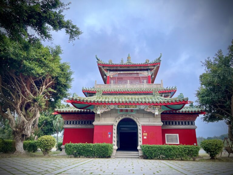 莒光樓正面全景，朱紅色樓閣翠綠屋頂，大樹環繞，金門一日遊地標