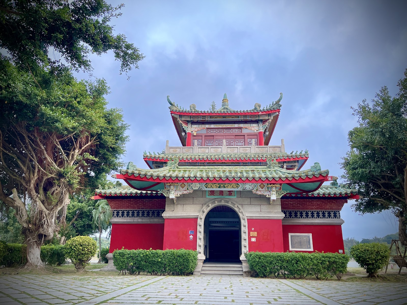 莒光樓正面全景，朱紅色樓閣翠綠屋頂，大樹環繞，金門一日遊地標