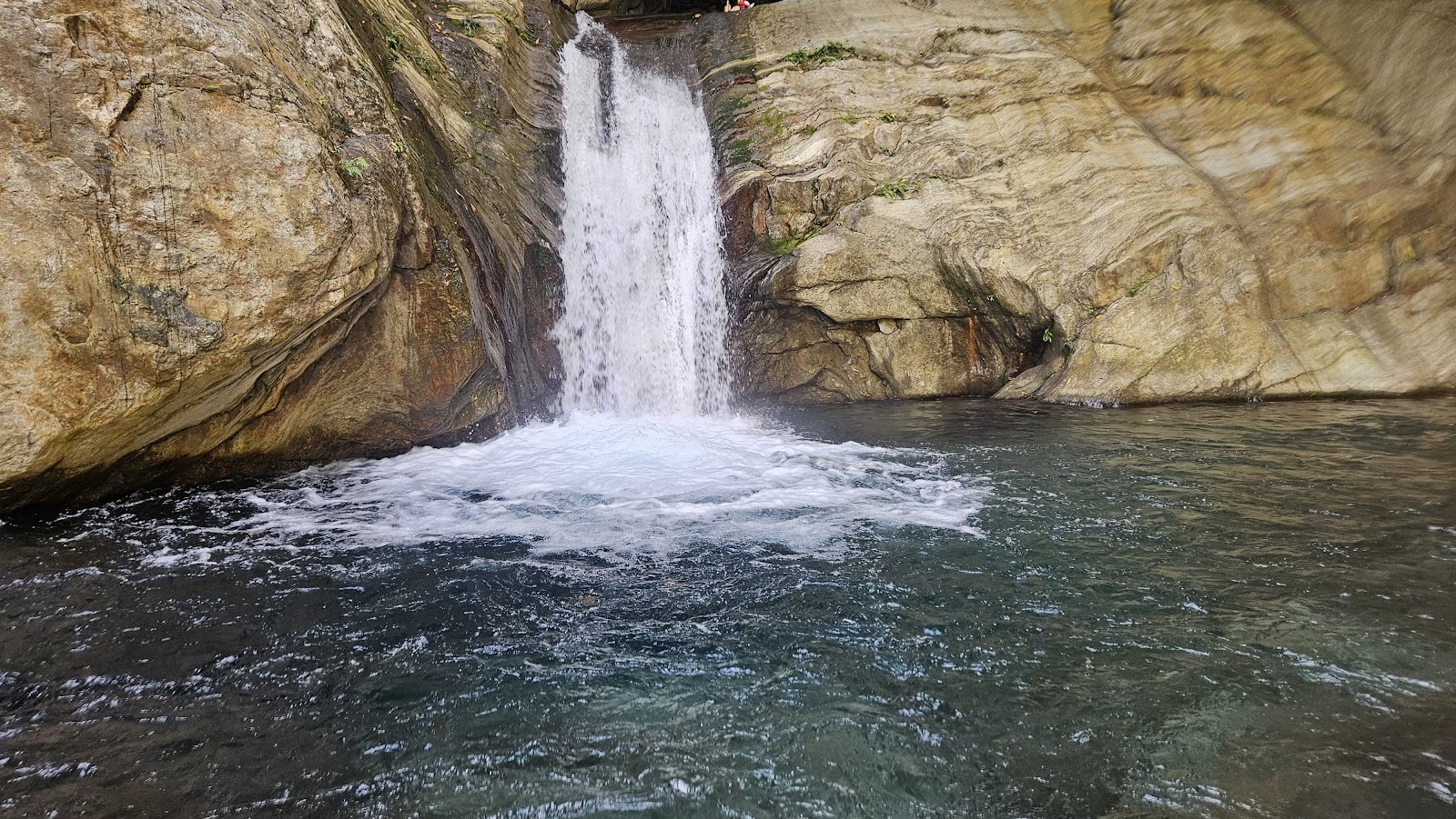 金岳瀑布正面全景，水流衝入碧藍水潭，兩側岩壁環繞，宜蘭南澳秘境瀑布