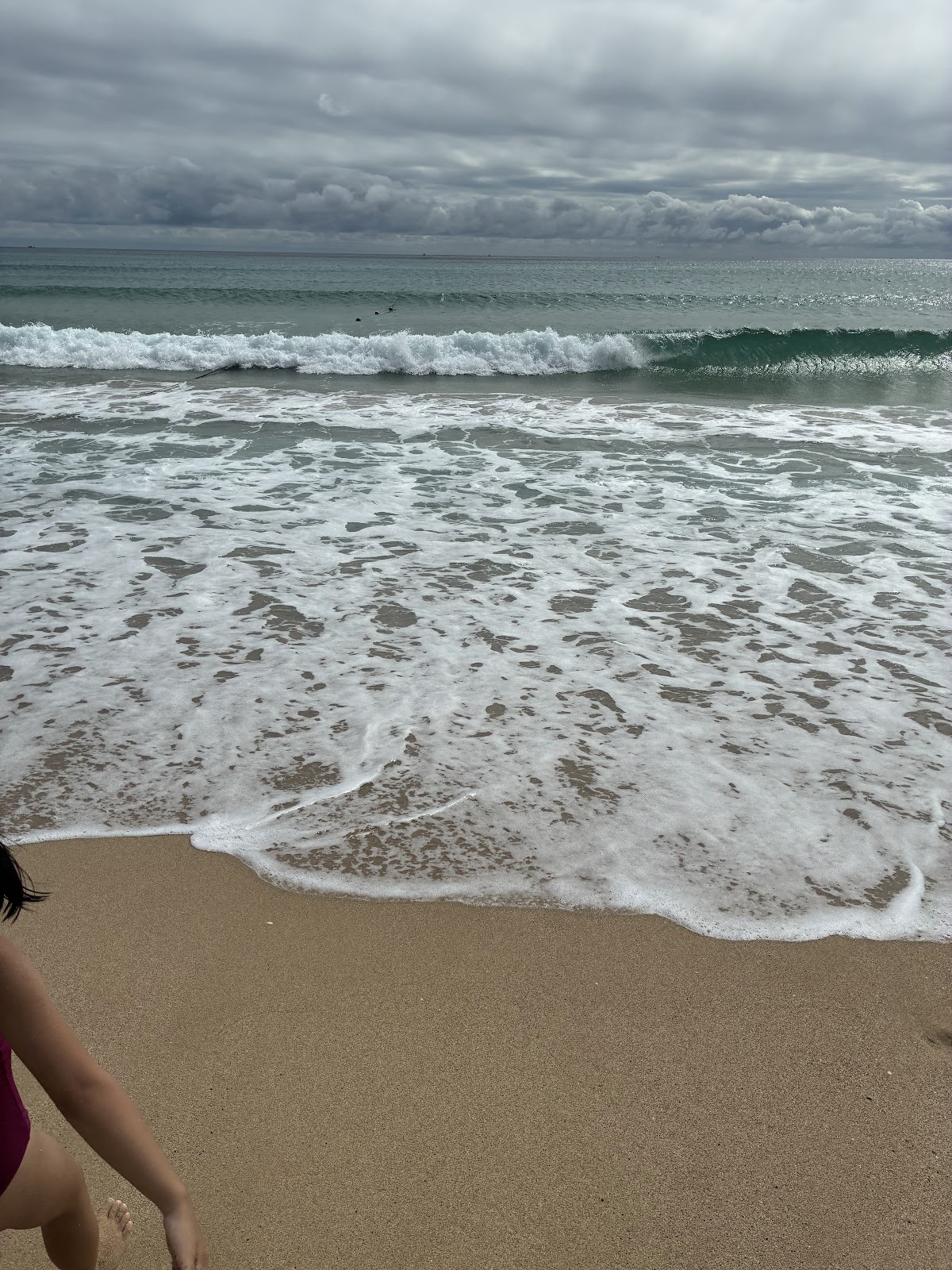 南灣沙灘海浪拍打岸邊,白色泡沫在細沙上漫延