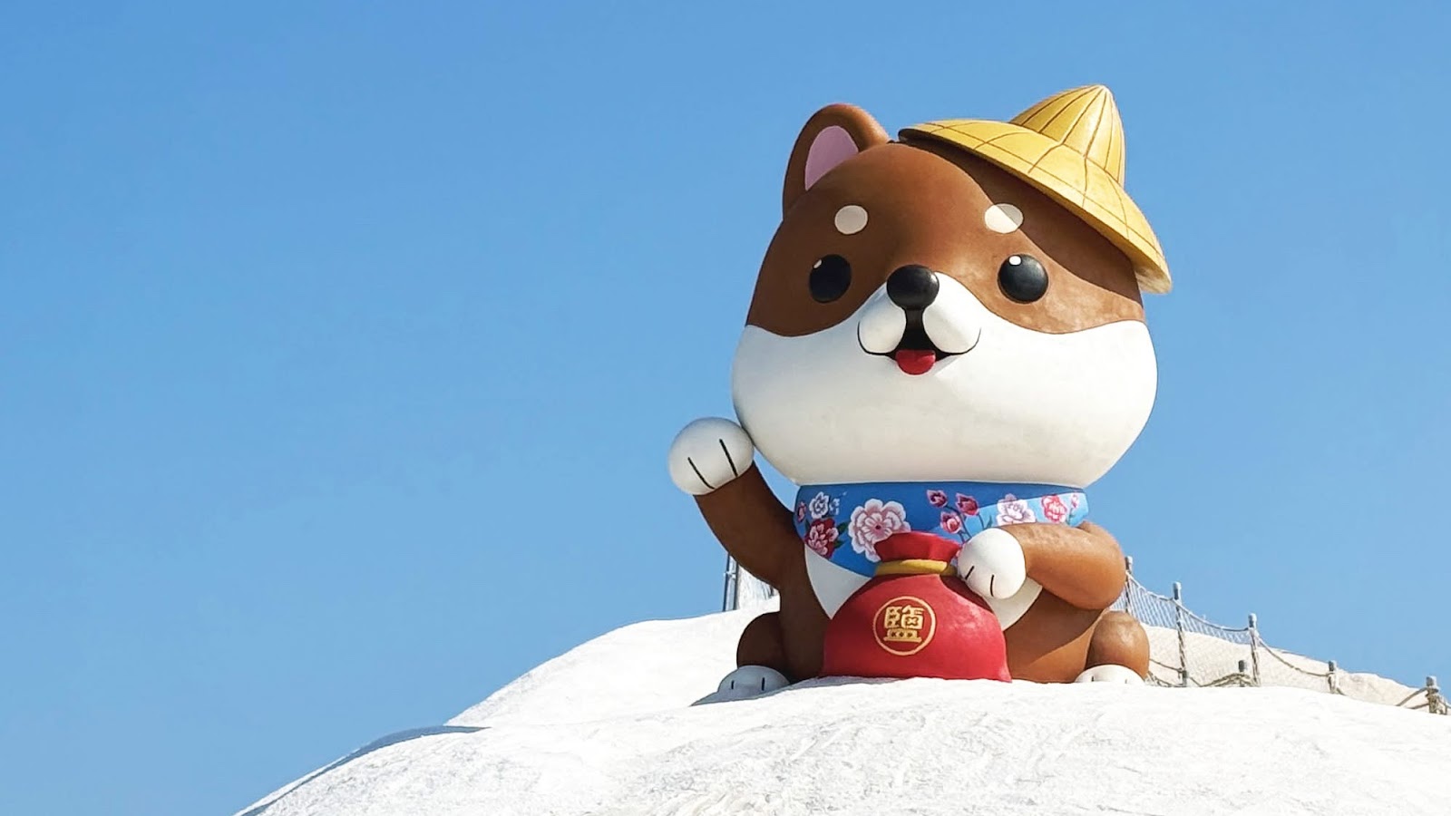 七股鹽山柴犬吉祥物特寫，戴斗笠抱鹽袋，站在白色鹽山頂