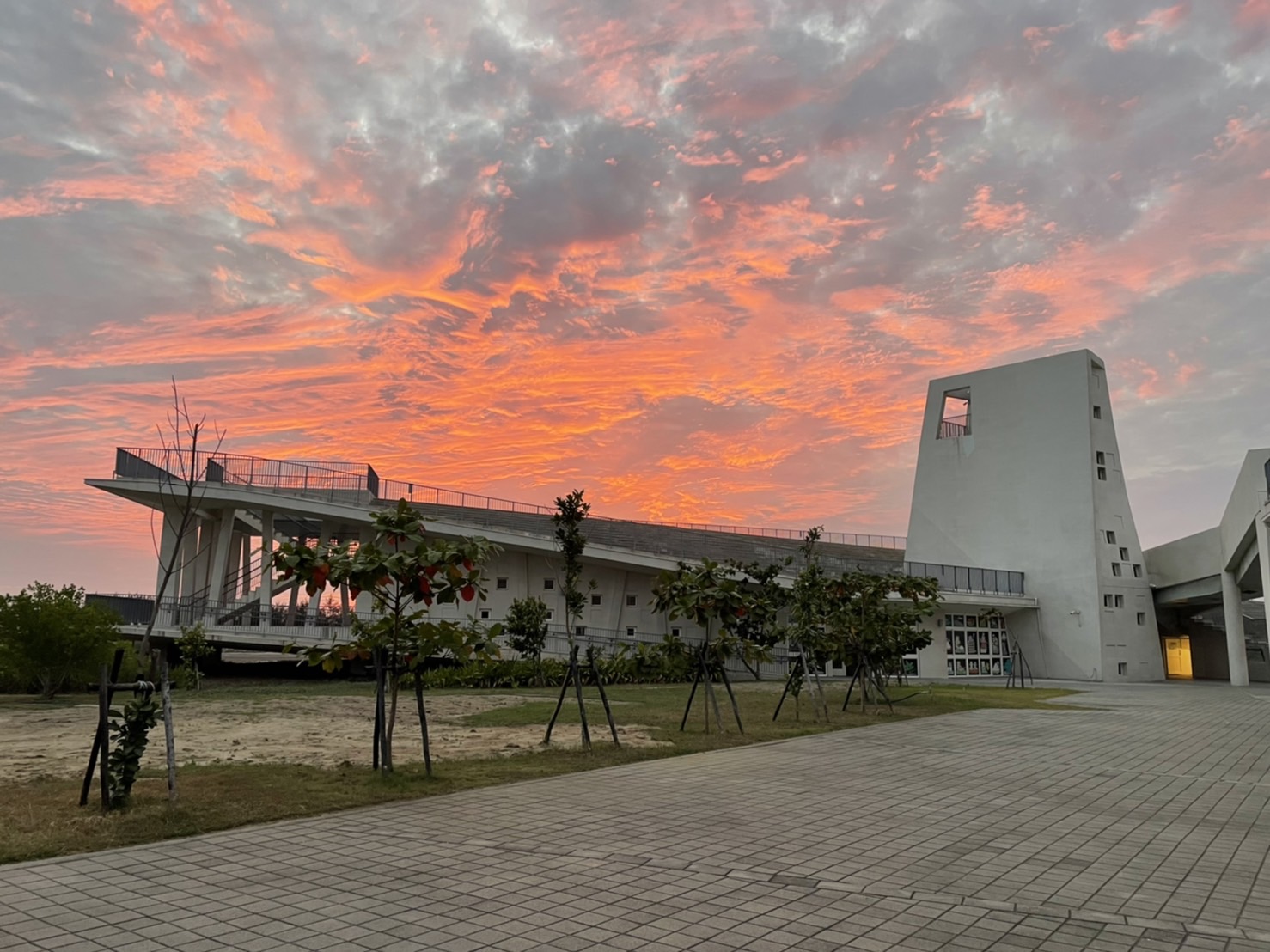 七股遊客中心現代建築，夕陽火燒雲橙紅天空，前景樹木廣場