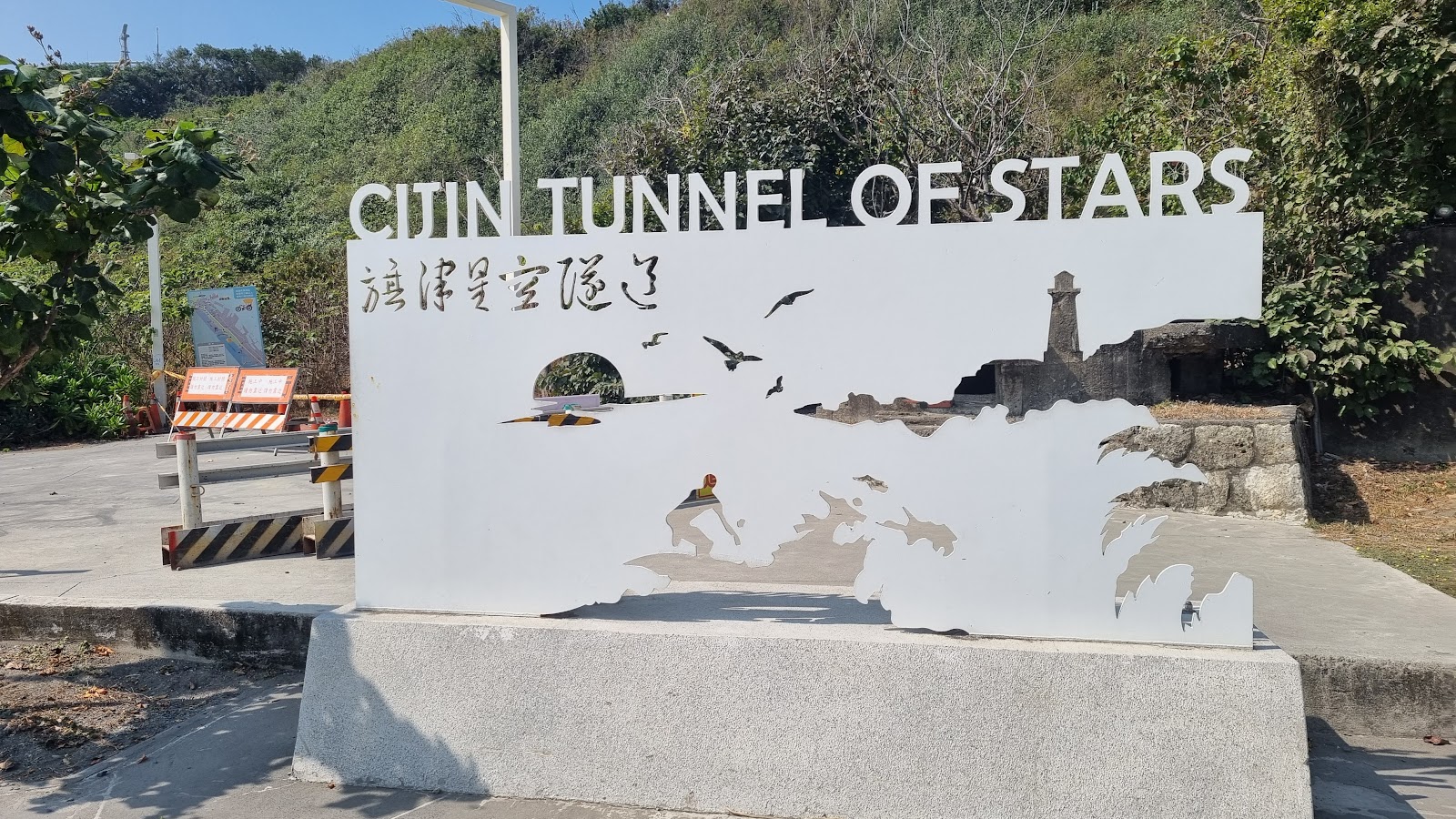 旗津星空隧道內部，黃橘暖光與綠光照亮石壁，木板棧道延伸至遠方