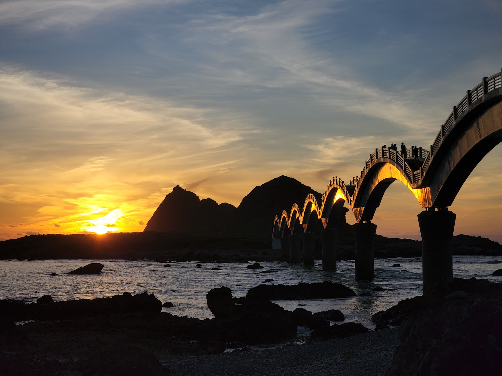 三仙台跨海步橋黃昏夕陽剪影，橋拱輪廓映照橘紅天空，台東三仙台一日遊必訪景點