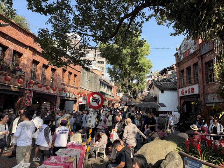深坑老街人潮熙攘的街道景象，兩側紅磚古厝林立，遊客漫步其中