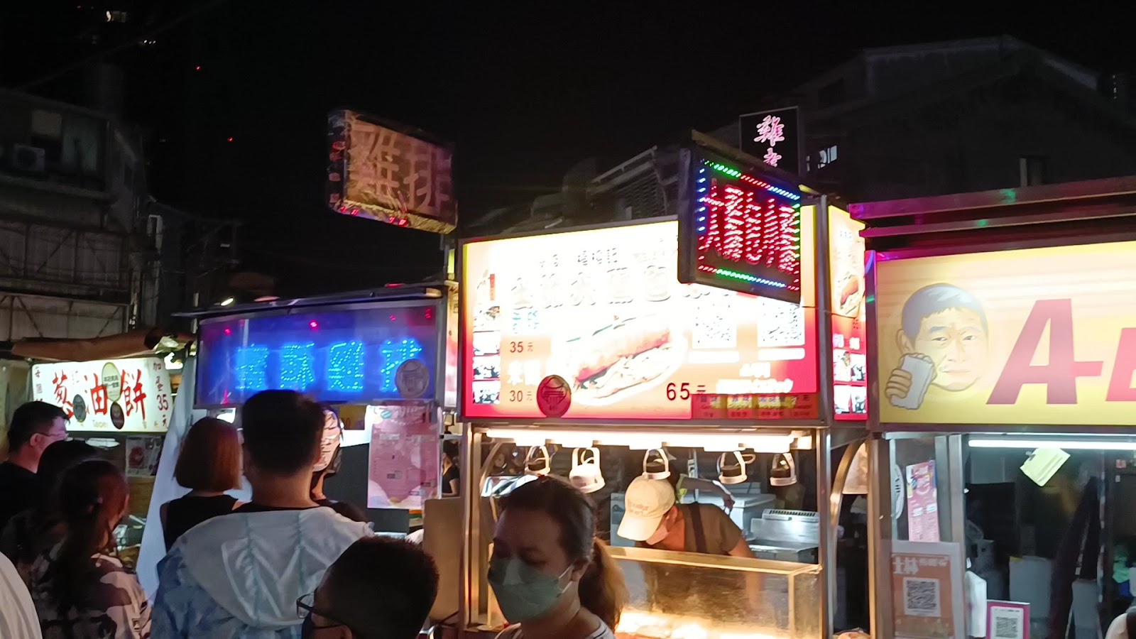 士林夜市攤販霓虹燈招牌,雞排攤油餅攤人潮排隊