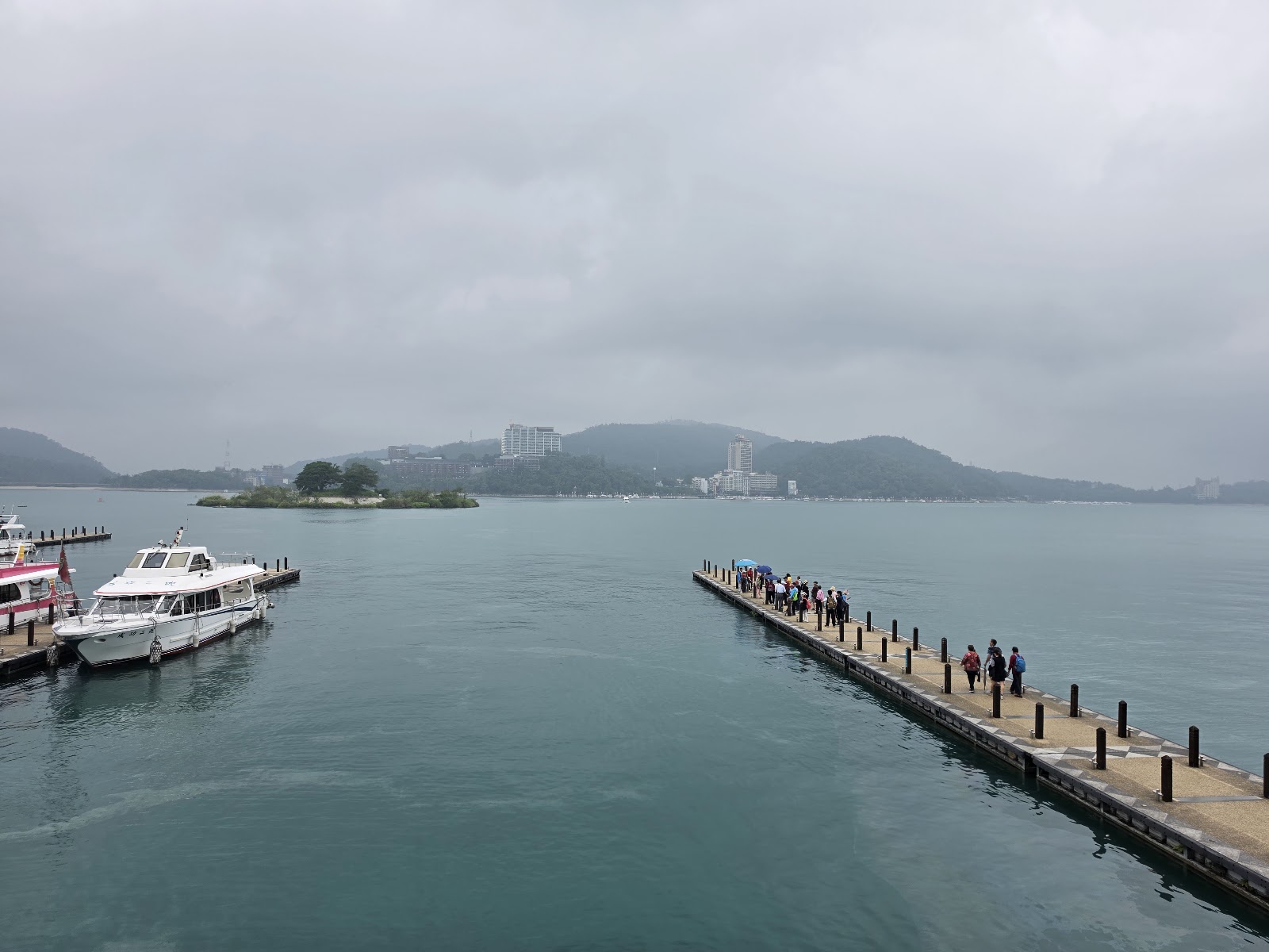 日月潭水社碼頭木棧橋，遊艇停靠湖面，晨霧繚繞，遠山層疊