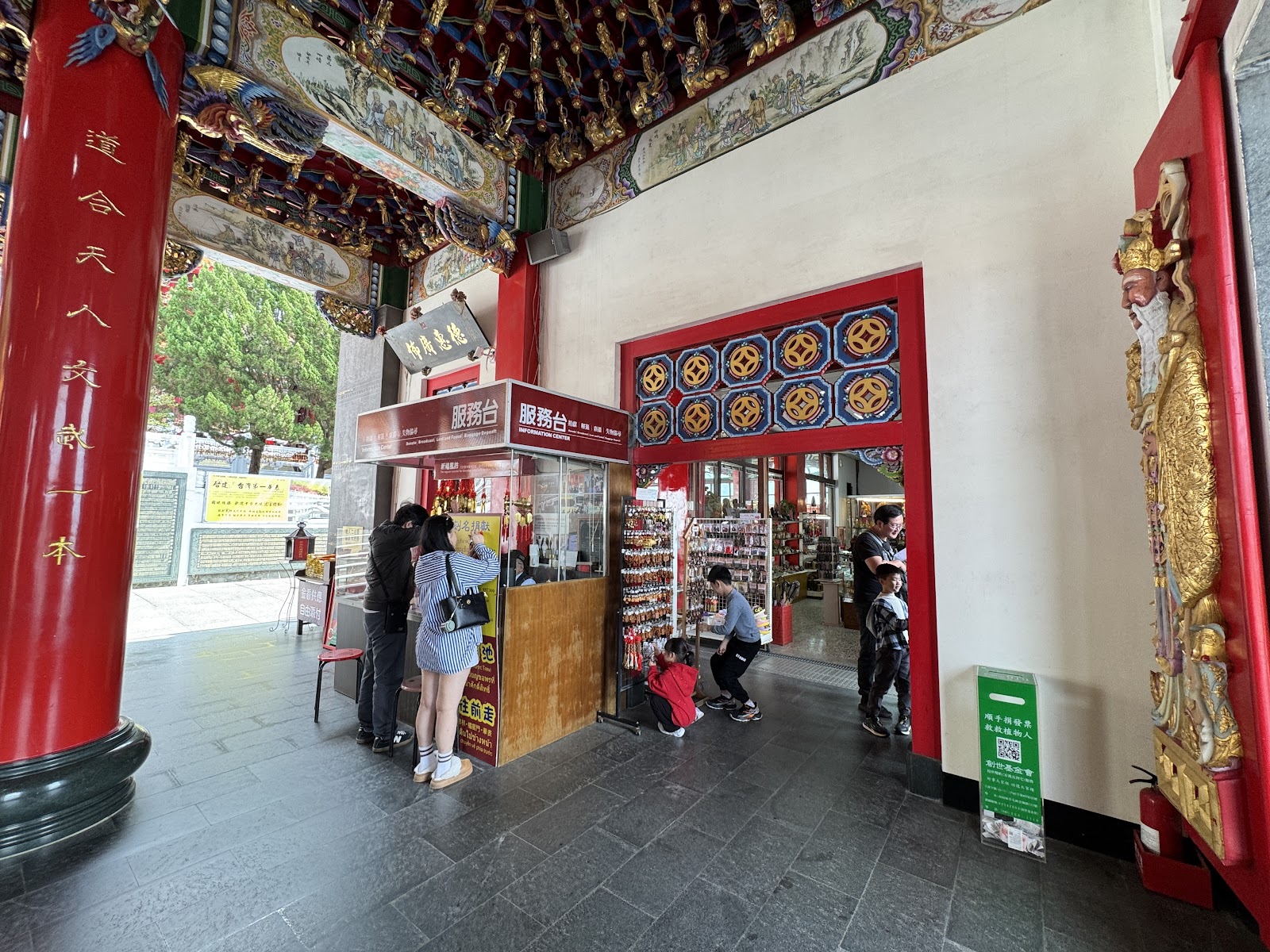 日月潭文武廟廊道服務台，紅柱彩繪廊頂，遊客在服務台前洽詢，右側金身神像