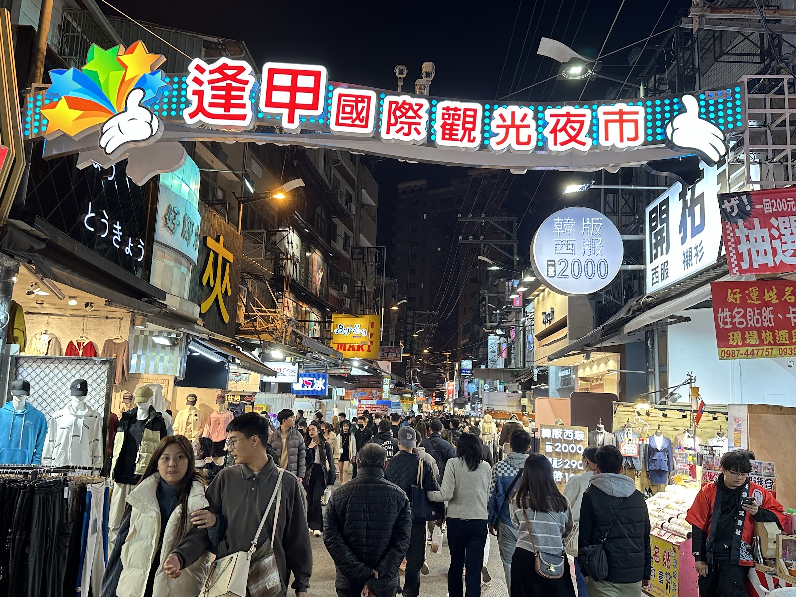 台中逢甲夜市入口拱門，夜晚人潮洶湧燈火輝煌