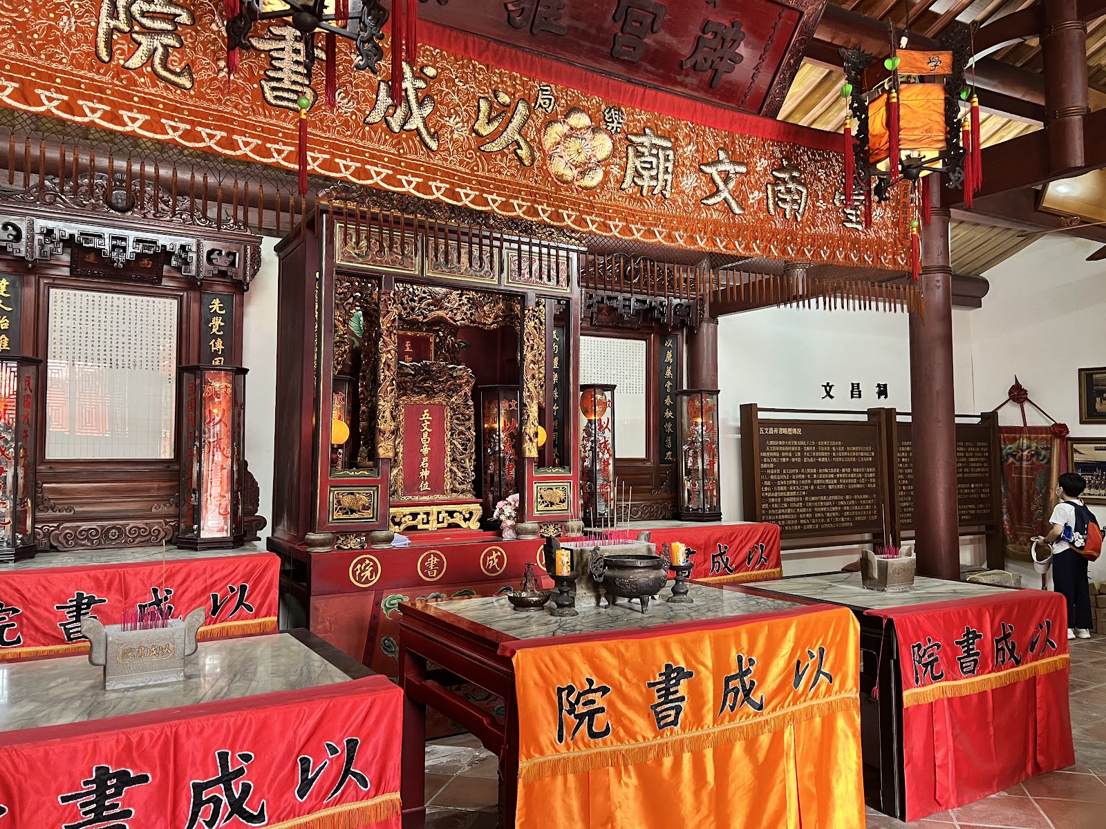 台南孔廟文昌祠內部，紅橙金色裝飾，神位供桌香爐，以成書院布幔，遊客參觀