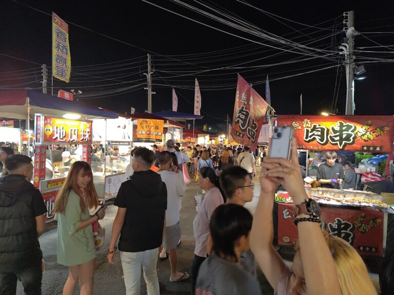 台南花園夜市夜晚街道全景，兩側攤販燈火通明，人潮熙攘